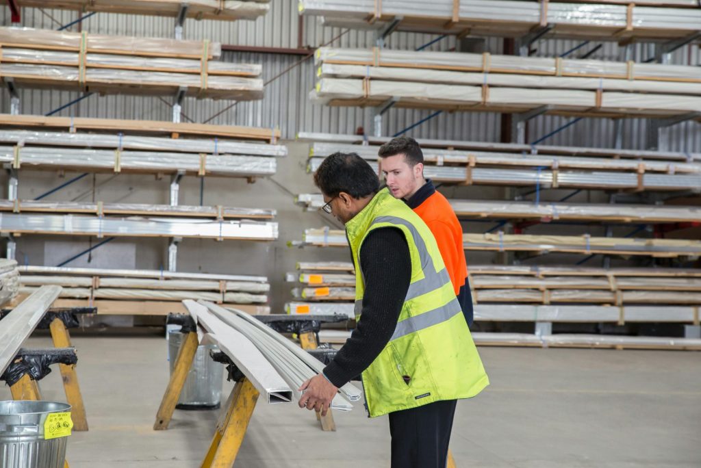 Two workers inspecting materials in a warehouse, focusing on quality control and inventory management.