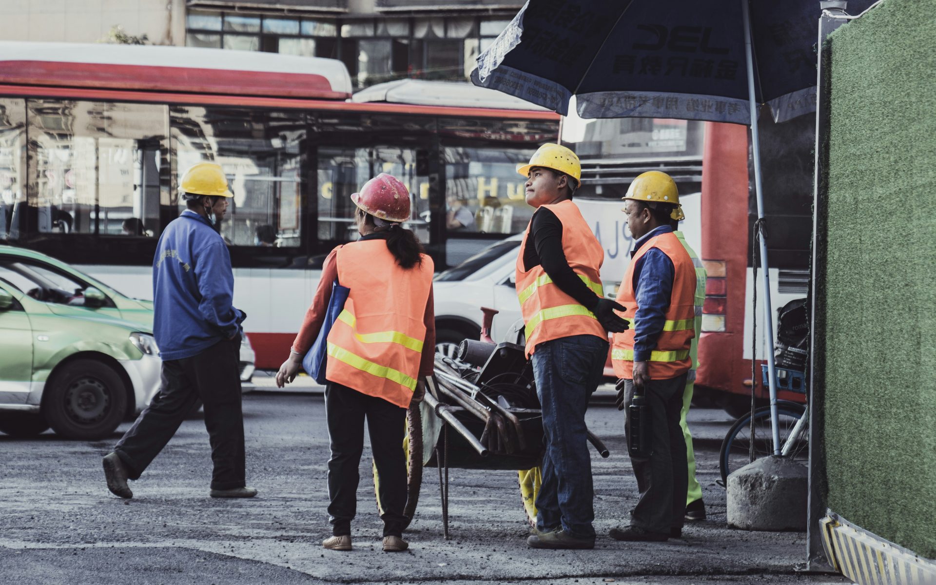 man in orange vest and black pants walking on sidewalk during daytime